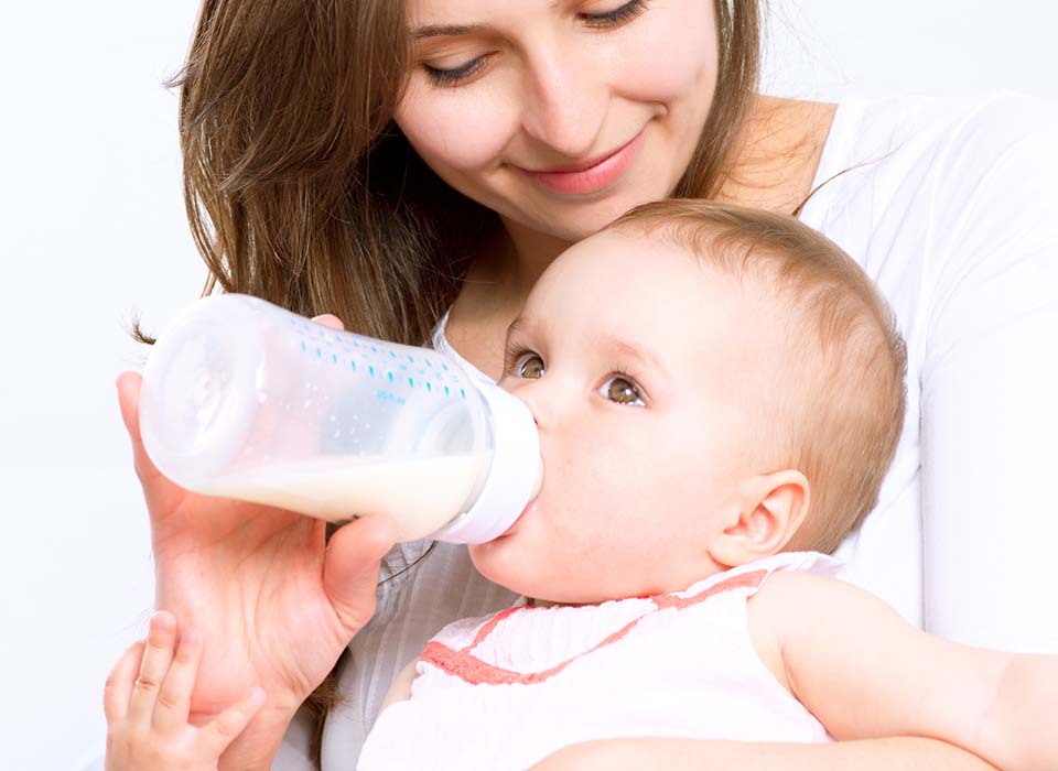 woman giving baby bottle with infant formula